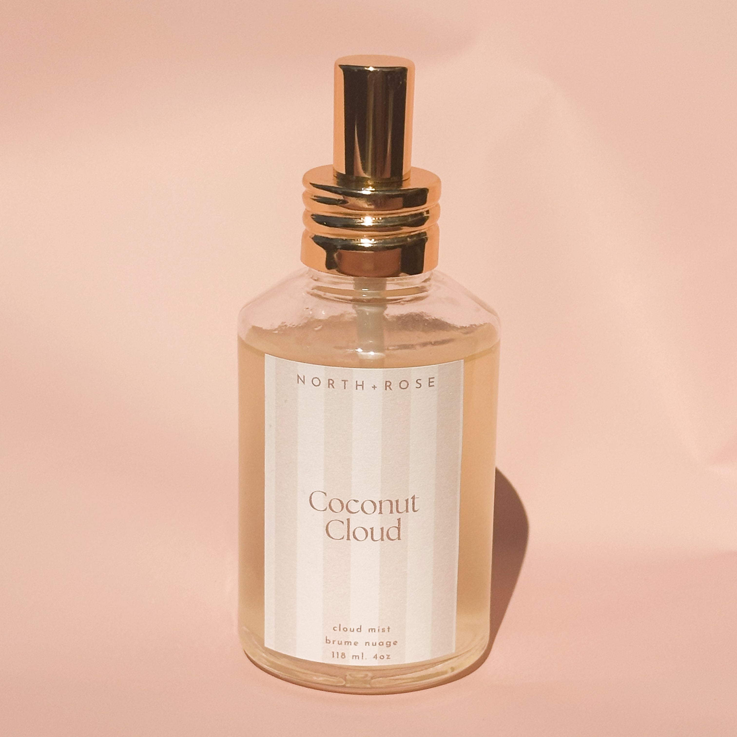 Perfume bottle labeled 'Coconut Cloud' by 'North+Rose' on a pink background